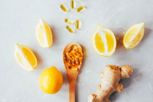 lemons, ginger root, spoon with supplements on, fish oil supplements, grey background
