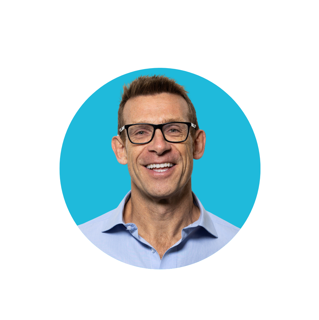 Damian Hopley, rugby player, wearing glasses and blue shirt smiling at the camera with a blue background
